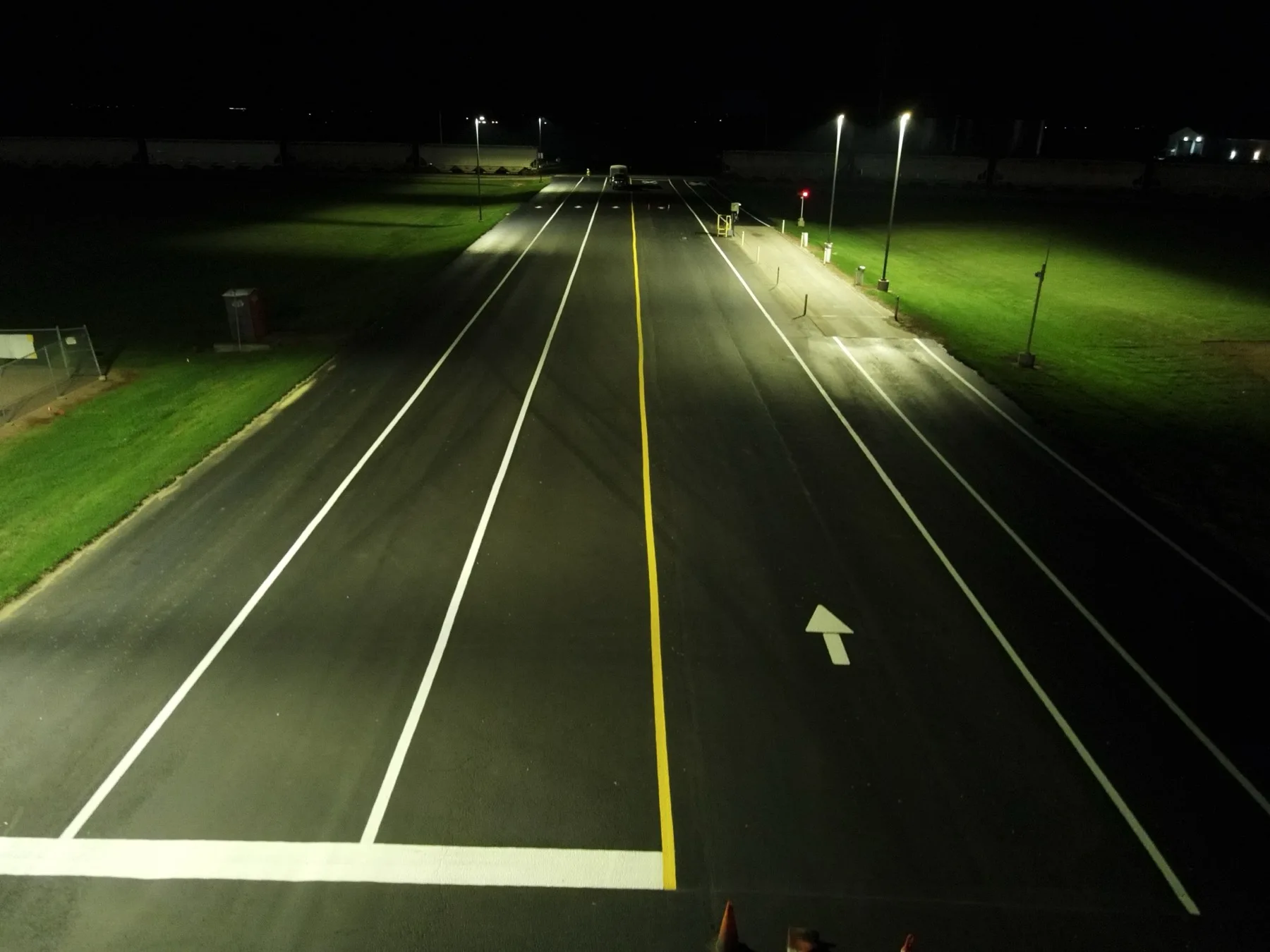 Fresh lane markings being laid at night under work lights